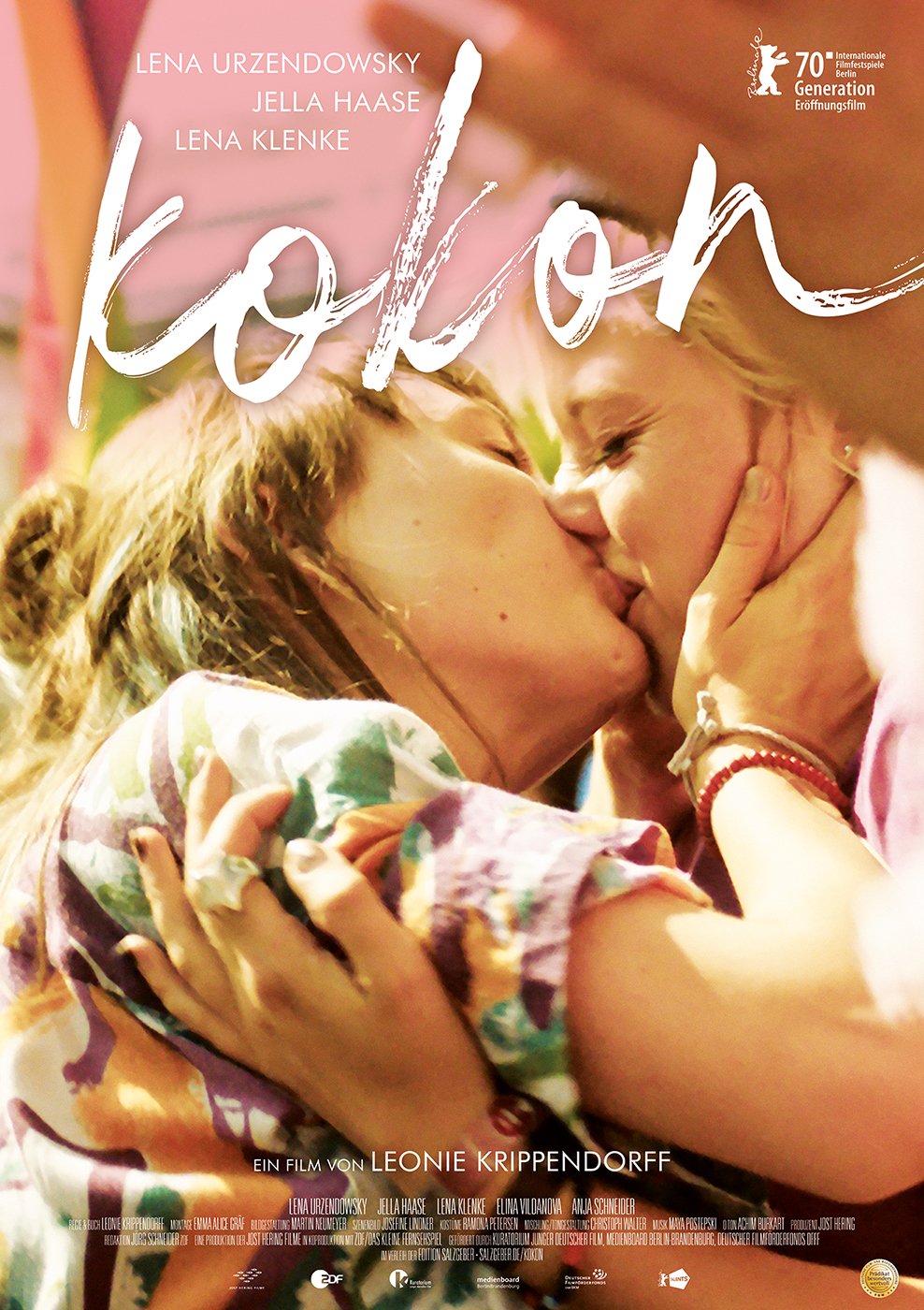 O título do filme, "Kokon", está escrito em letras grandes e estilizadas na cor branca, em um estilo quase manuscrito.  As letras são grossas e irregulares, transmitindo uma sensação de leveza e informalidade.

Na parte inferior, há uma informação em alemão indicando que é um filme de Leonie Krippendorff e lista os nomes das atrizes: Lena Urzendowsky, Jella Haase e Lena Klenke.  Há também diversos logos menores, que provavelmente indicam premiações, produção, e distribuição.

A imagem principal do pôster mostra duas jovens mulheres se beijando com afeto.  Estão abraçadas, e a fotografia tem uma tonalidade quente, quase amarelada, dando uma sensação de intimidade e aconchego.  A composição é próxima, focando no beijo e nos rostos das jovens.  Seus cabelos são claros e compridos.  A vestimenta delas parece casual e informal.  Uma delas usa um bracelete no pulso.

No canto superior direito, existe um pequeno selo em alemão, indicando que o filme foi um dos filmes de abertura do festival internacional de cinema de Berlim (Berlinale) na seção “Generation”.